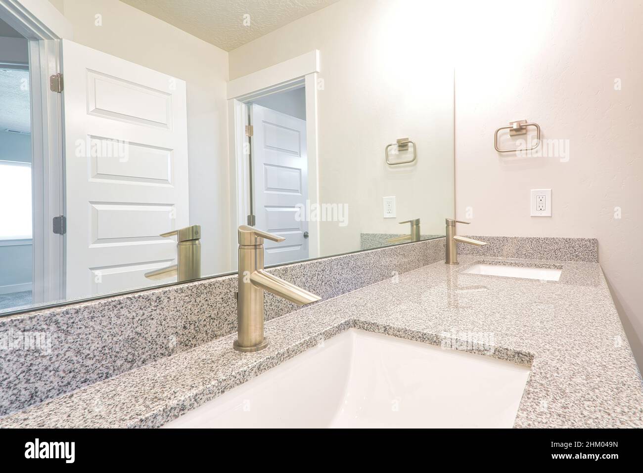 Double sink with rectagular undermount bowl and large mirror of bathroom. Close up of the gray countertop with built in clean basin and stainless stee Stock Photo