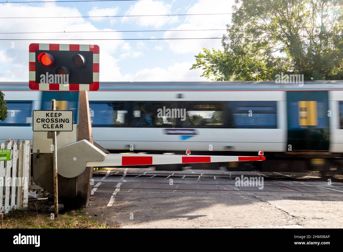A Great Northern train speeds past a closed level crossing near Harston in Cambridgeshire, UK Stock Photo
