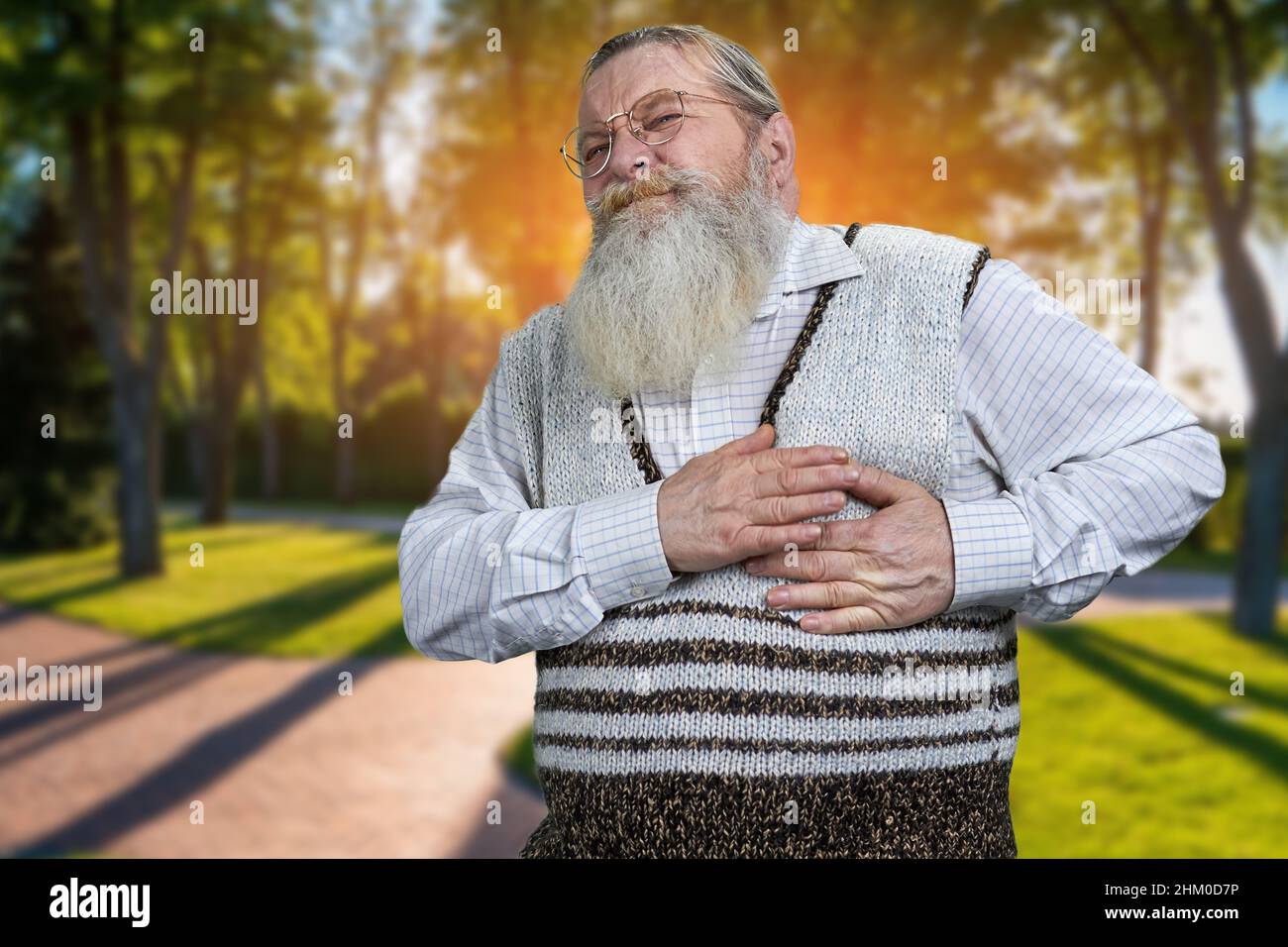 Senior man suffering from heart attack. Spring park in the background. Health care of the elderly people. Stock Photo
