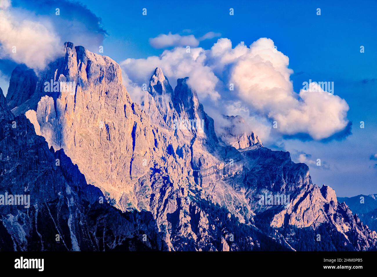Campanile and Cima di Val di Roda (middle), Sass Maor and Cima della Madonna (right), main summits of the Pala group, covered in clouds, at sunset. Stock Photo
