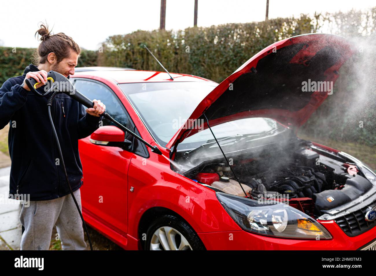 Woodbridge, Suffolk, UK February 24 2021: A young man pressure washing his car clean Stock Photo