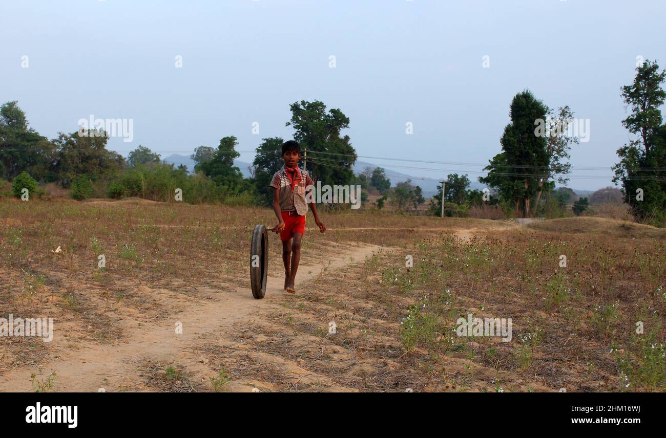 A boy playing with a motor cycle tyre in a rural village. Javadhu Hills