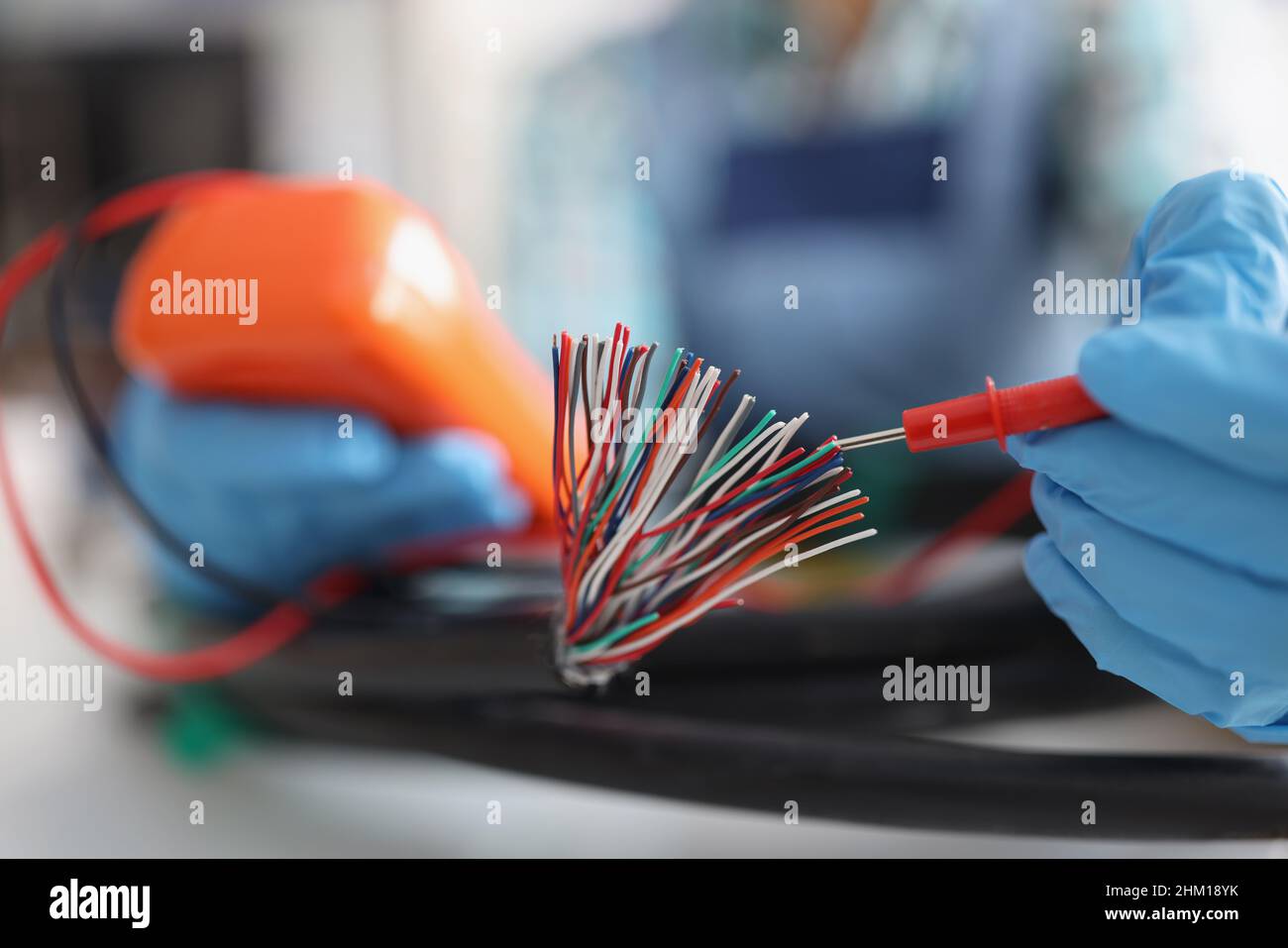 Hands with a voltmeter check colored wires in the cable, blurry Stock Photo