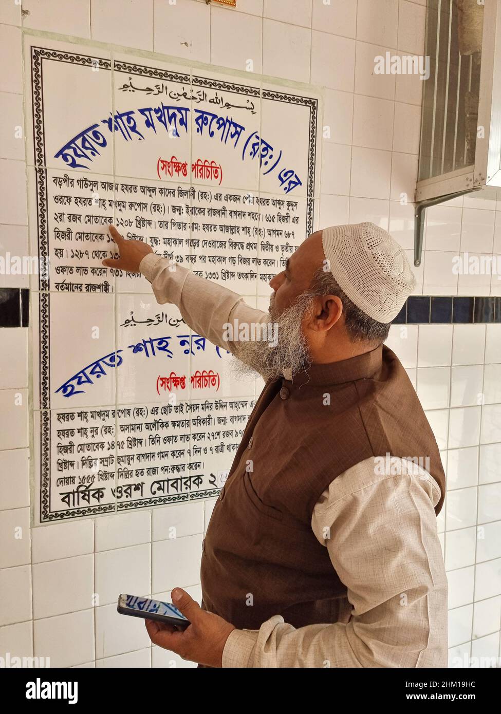 Current disciple of the Holy Saint, Shah Makhdum, traces the saint's genealogy on the chart fixed to the wall of the saint's mazaar (tomb), Rajshahi. ‘Abd al-Quddūs Jalāl ad-Dīn best known as Shah Makhdum and also known as Rupos, was a Sufi Muslim figure in Bangladesh. He is associated with the spread of Islam into the Varendra region of Bengal. He arrived in Bengal with his elder brother Syed Ahmad (Miran Shah) from Baghdad. Shah Makhdum Airport of Rajshahi, is named after him. Bangladesh. Stock Photo