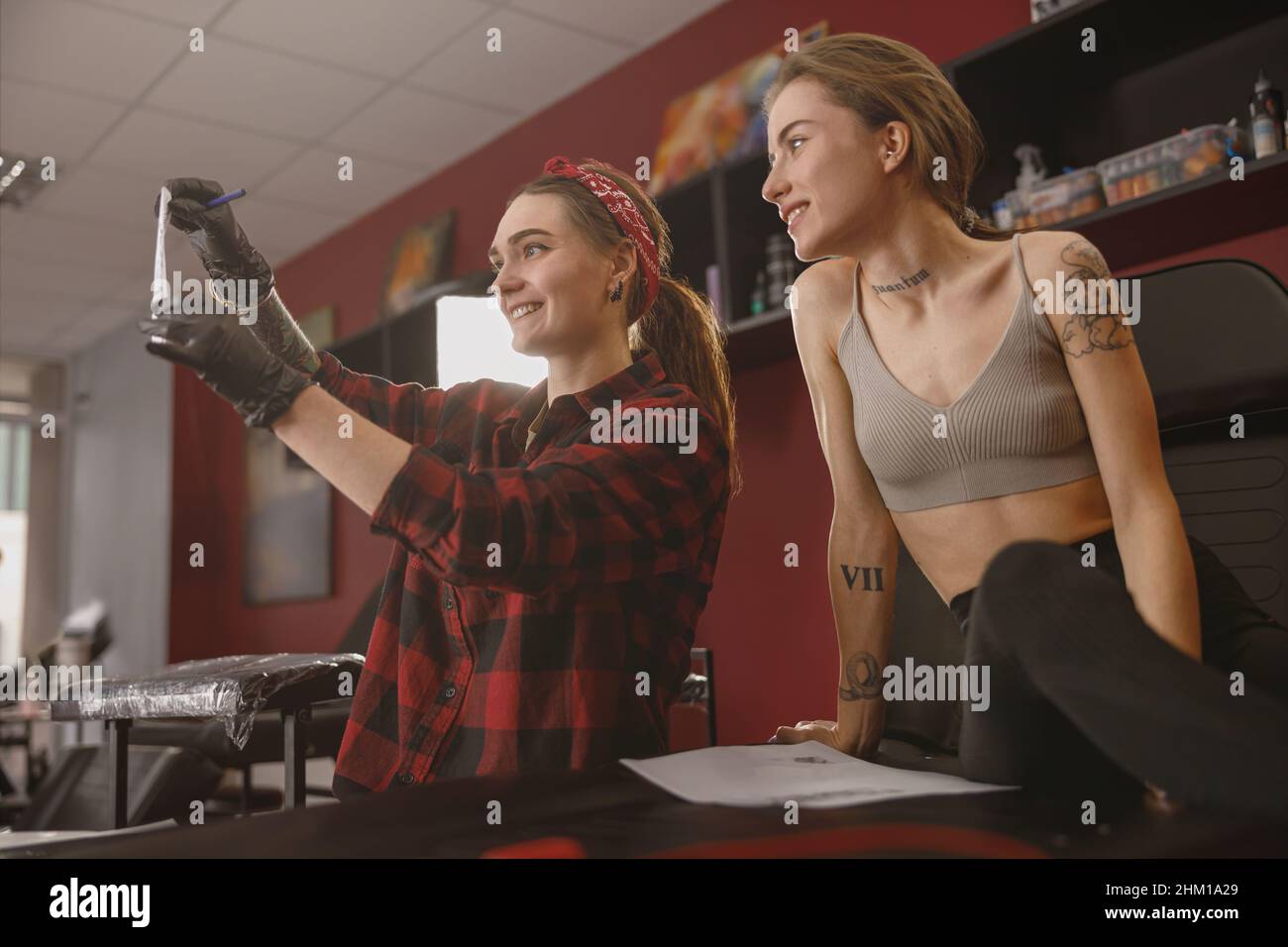 Young female tattoo master showing client drawn sketch Stock Photo - Alamy