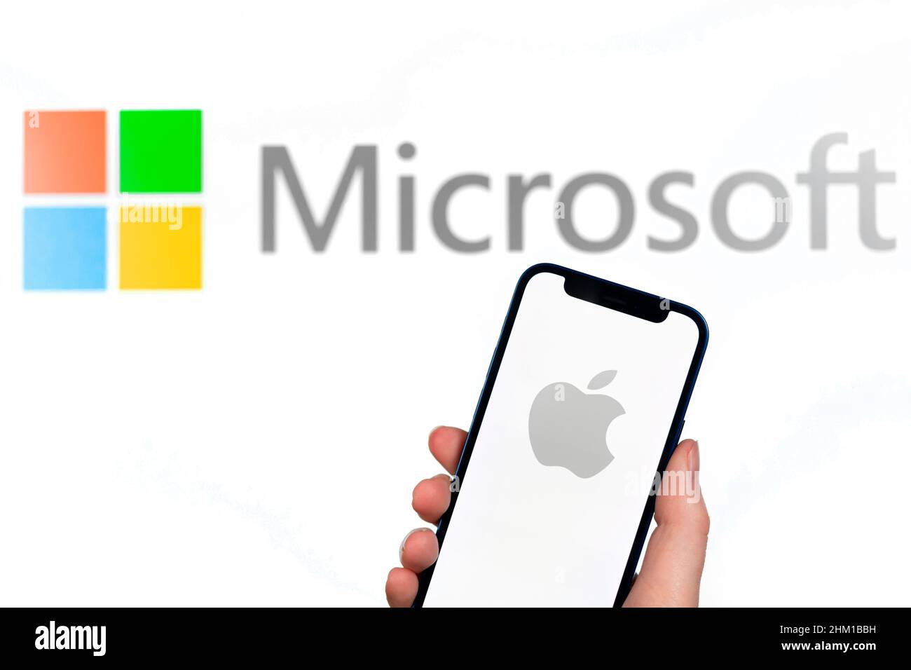 Apple and Microsoft logo. Hand with mobile phone, business concept photo Stock Photo