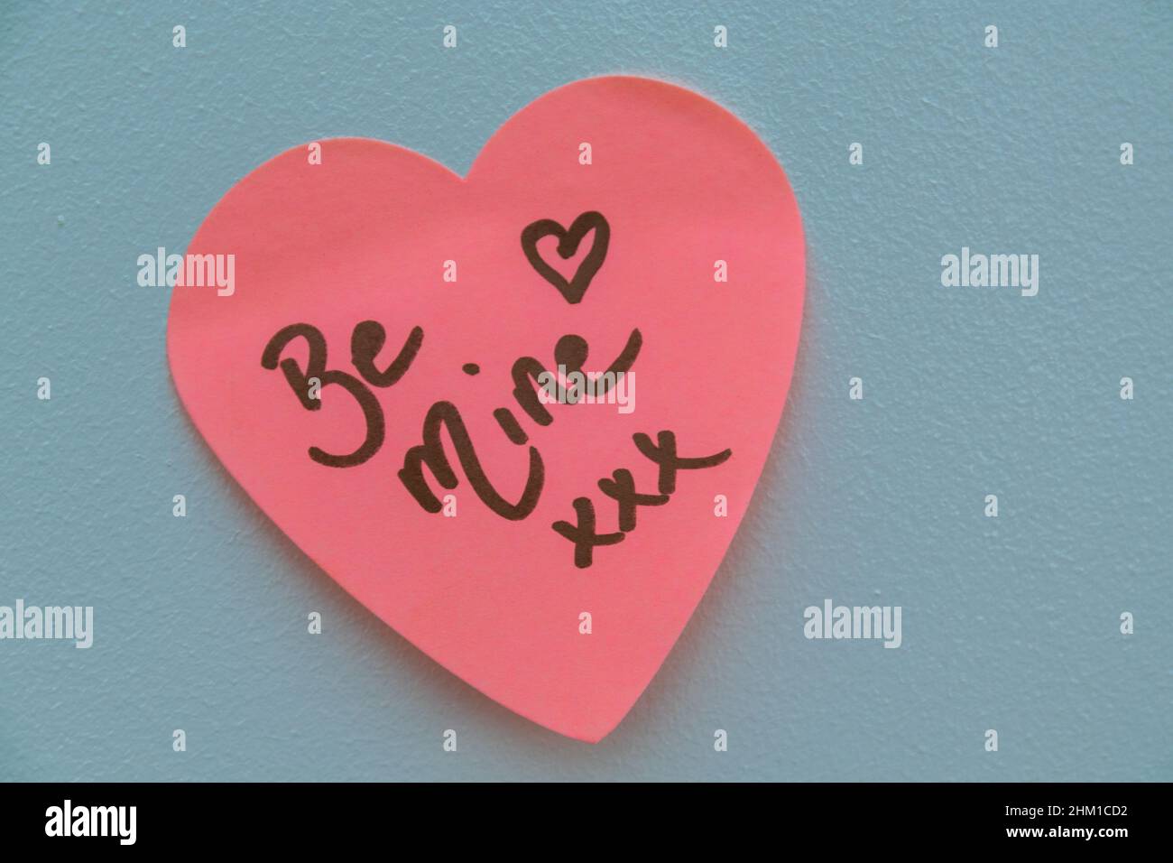 Be Mine hand wrote text on pink love heart with drawn hearts. On white isolated background. Love Valentines concept. Stock Photo