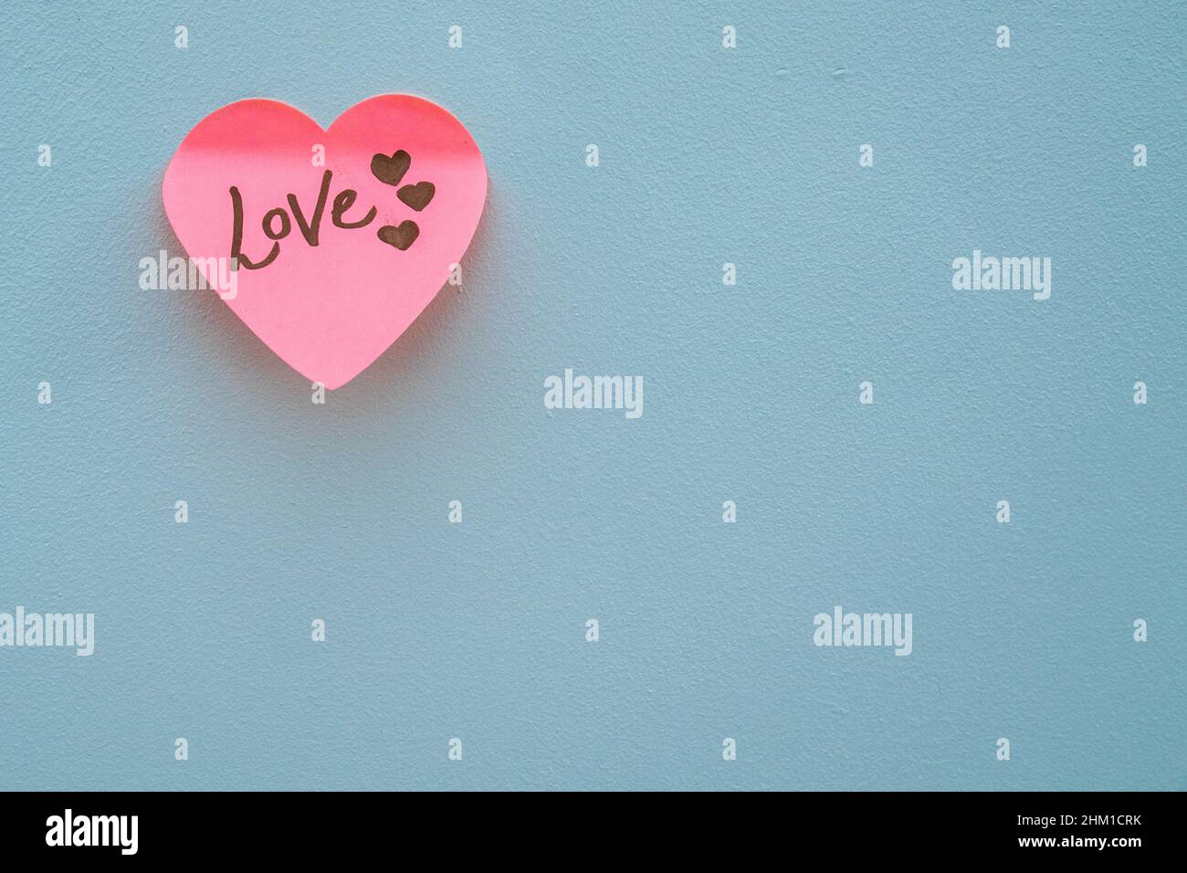 Love hand wrote text on pink love heart with drawn hearts. On white isolated background. Love Valentines concept. Stock Photo