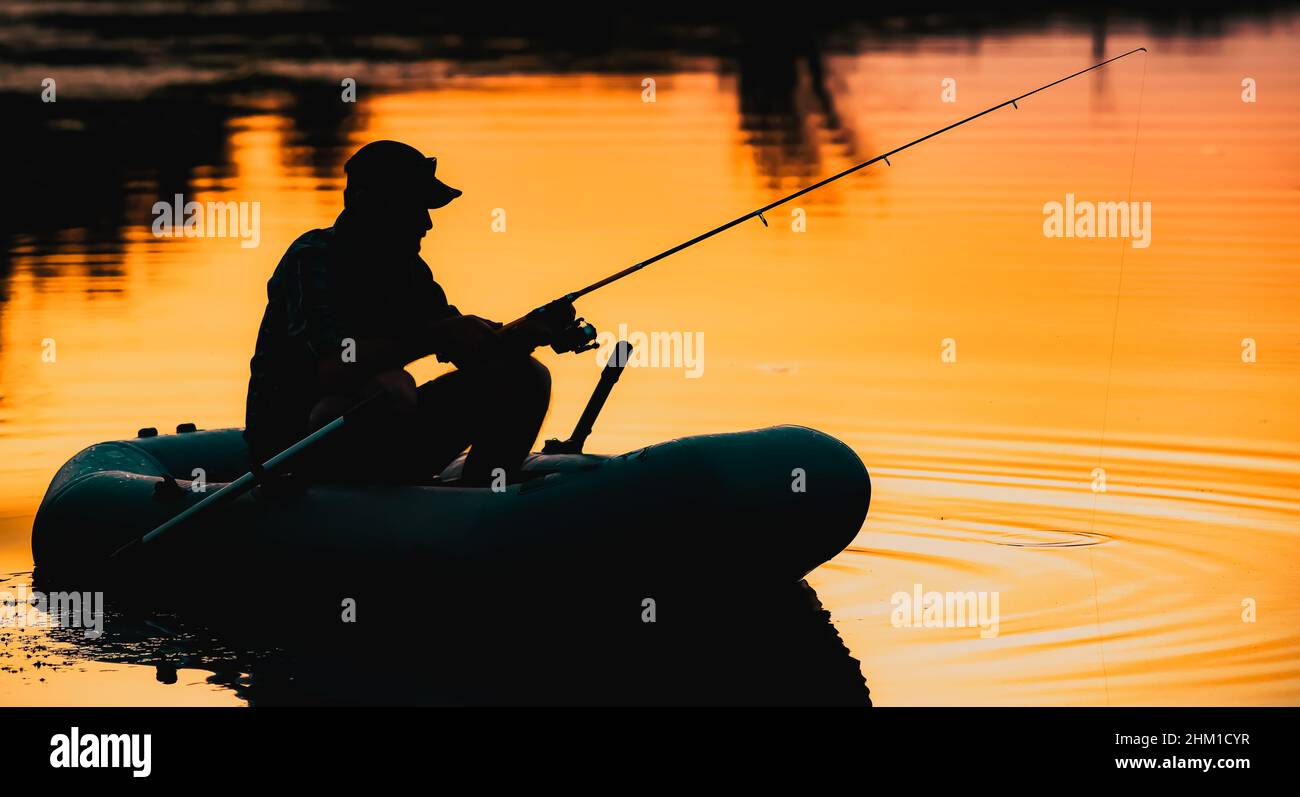 fisherman silhouette in a boat fishing on a lake at sunset Stock Photo ...