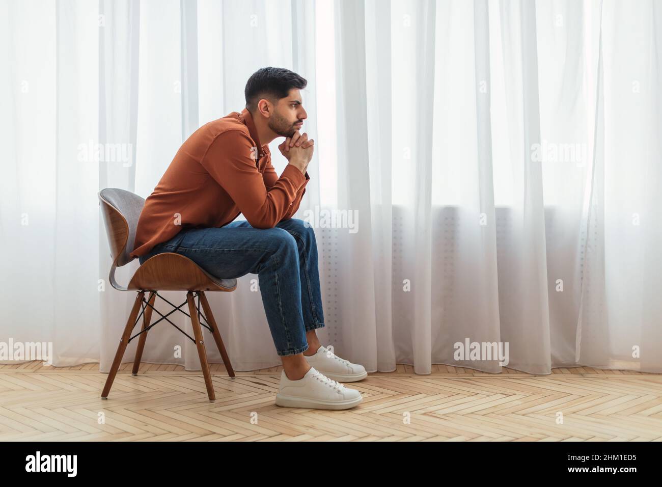 Pensive Arab man sitting on chair and thinking Stock Photo