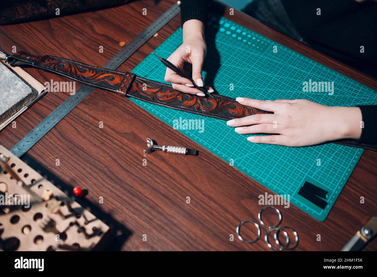 Tanner woman making leather bag belt pattern on Working