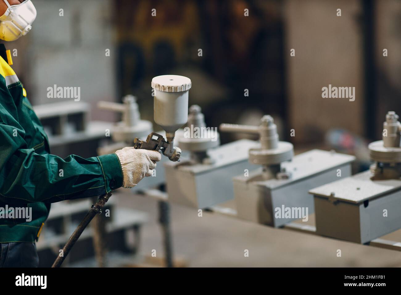 Powder primer coating of metal parts. Worker man in a protective suit