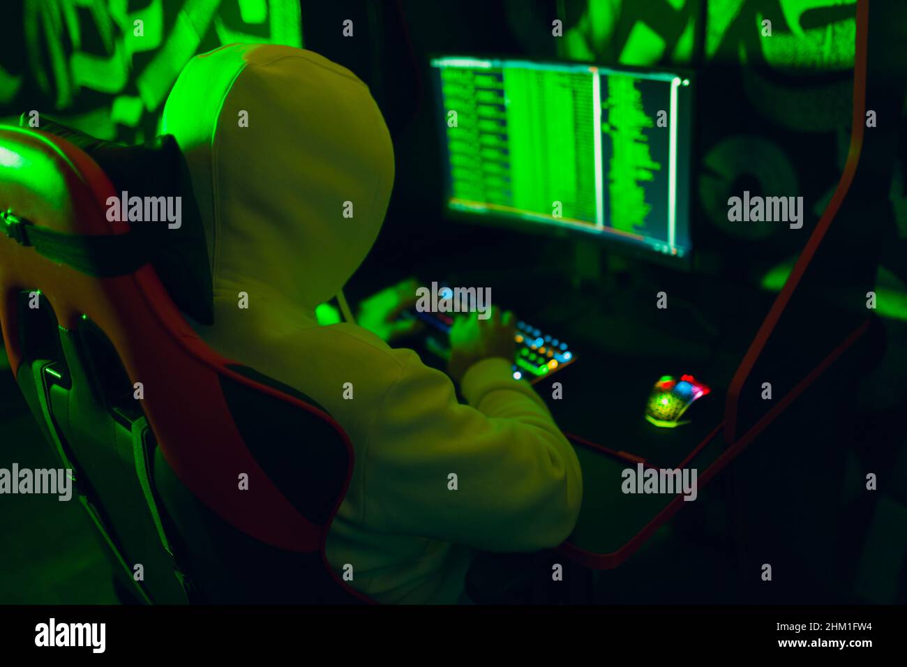 Hacker using computer malware software and hacking binary code green digital interface. Stock Photo