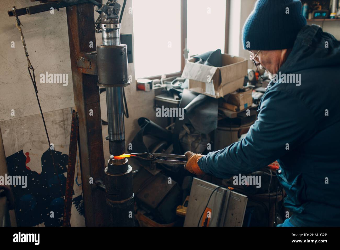 Blacksmith and makes metal detail with automatic hammer and