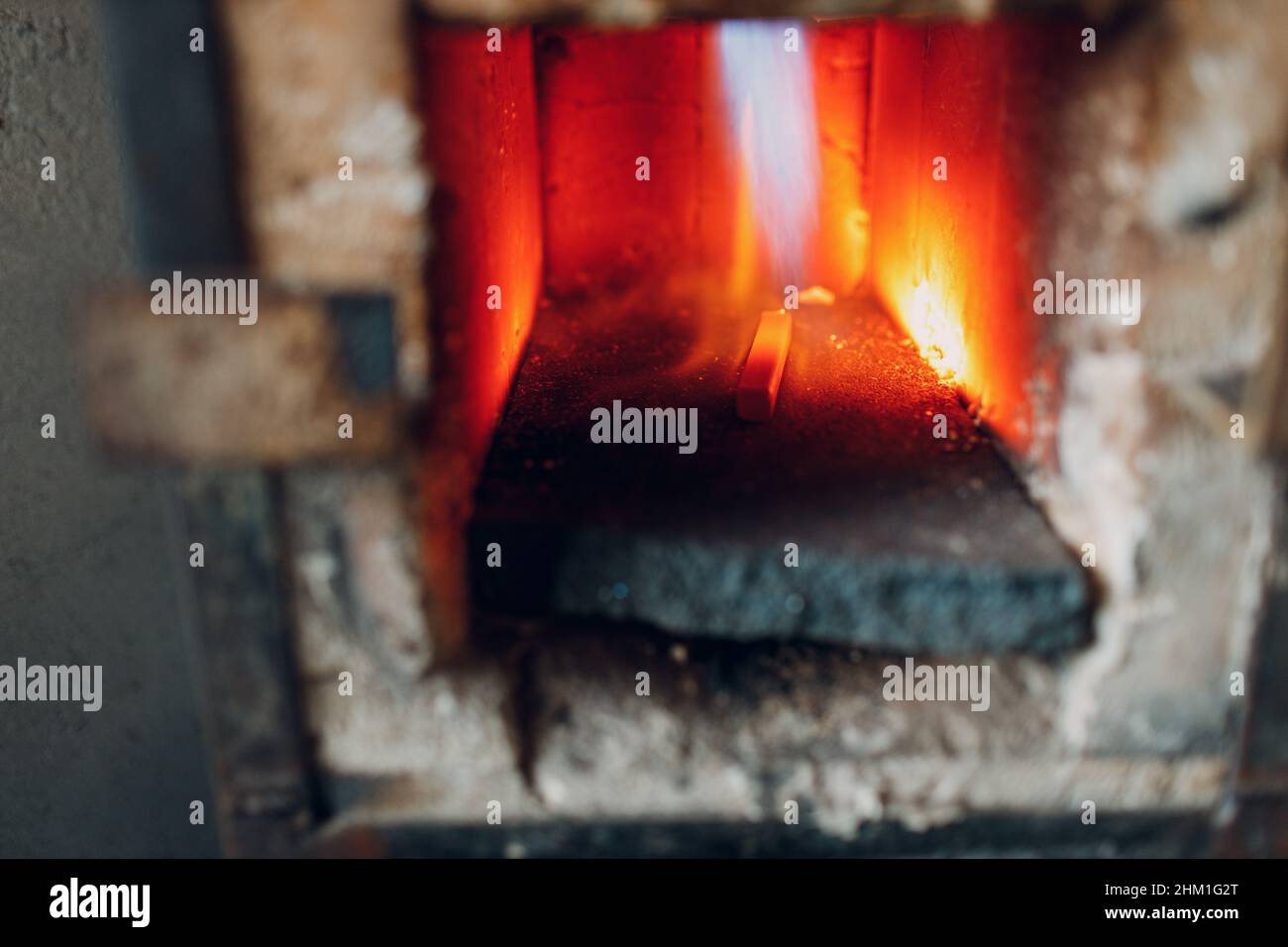 Blacksmith forge oven with hot flame. Smith heating iron piece of steel ...