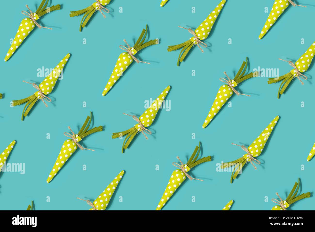 Green fabric carrots pattern on a turquoise background. Spring, Easter minimal flat lay. Stock Photo