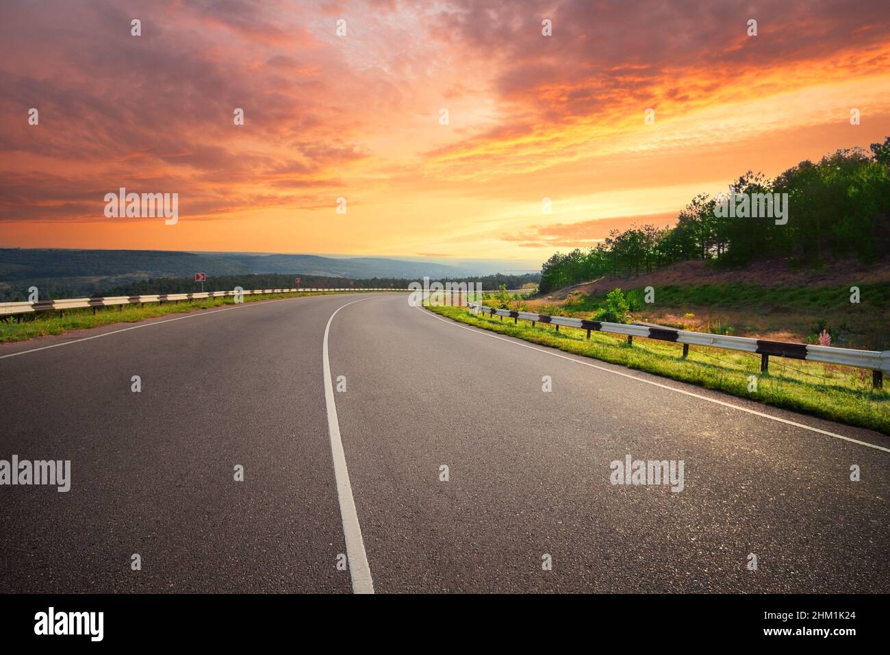 Curving asphalt road under dramatic sunset sky Stock Photo - Alamy