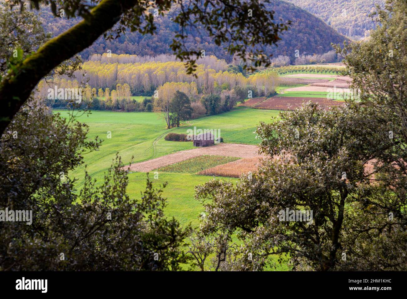 View on a single barn in the Perigord countryside, France taken through foliage from a cliff on a partly overcast autumn afternoon Stock Photo