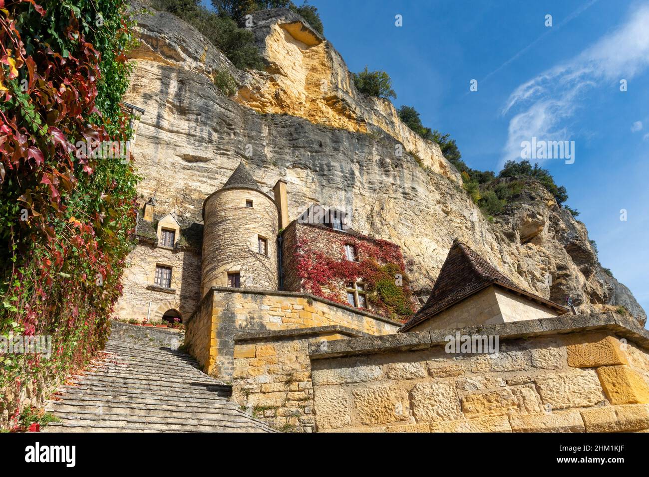 Limestone cliff and historic houses made of yellow stones of La Roque-Gageac, Perigord, taken on a sunny autumn afternoon Stock Photo
