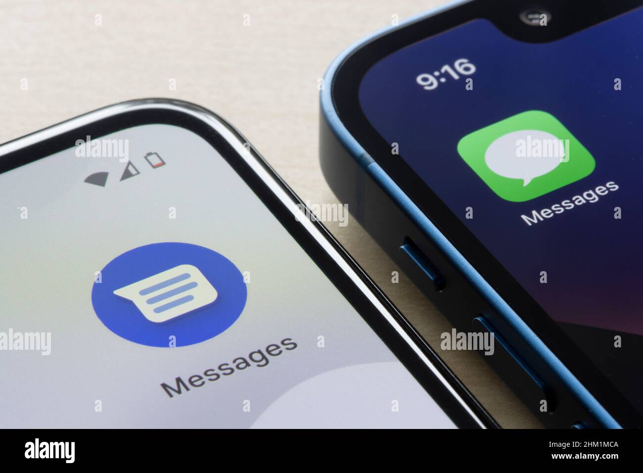 Google Messages and Apple's iMessage app icons are seen respectively on a Google Pixel 4a smartphone and an iPhone 13 mini. Android vs iOS concept. Stock Photo