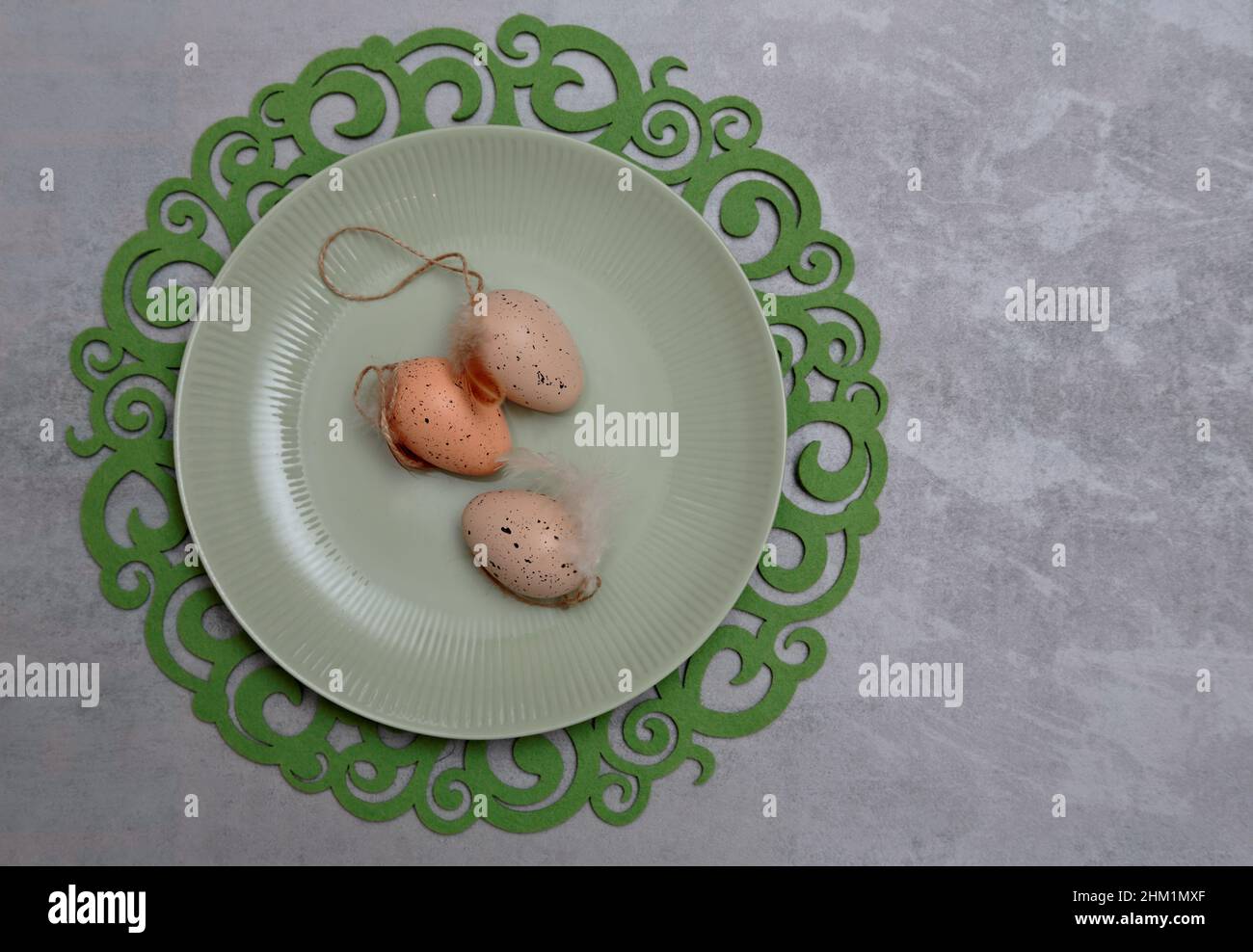Three Easter eggs on a greenish plate and decorative tablet Stock Photo