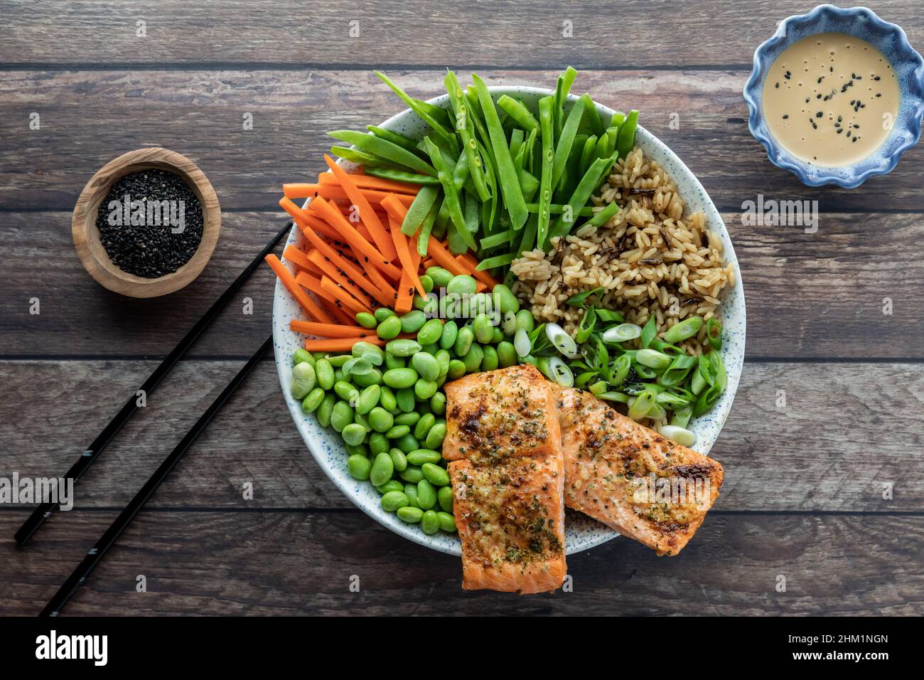 Top down view of an Asian salmon salad bowl with dressing and black sesame seeds Stock Photo