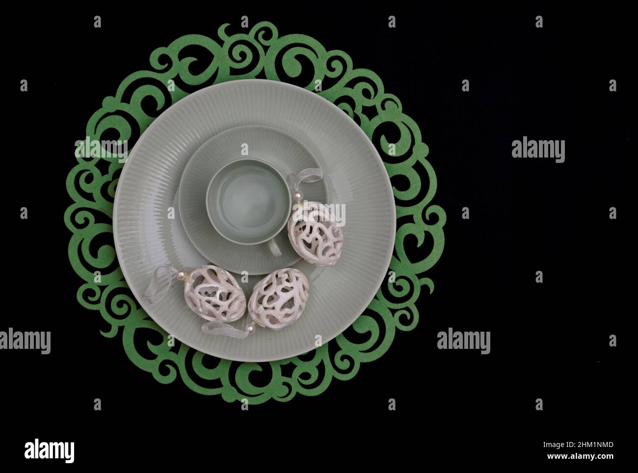 Three white easter eggs and an empty coffee cup on a greenish plate Stock Photo