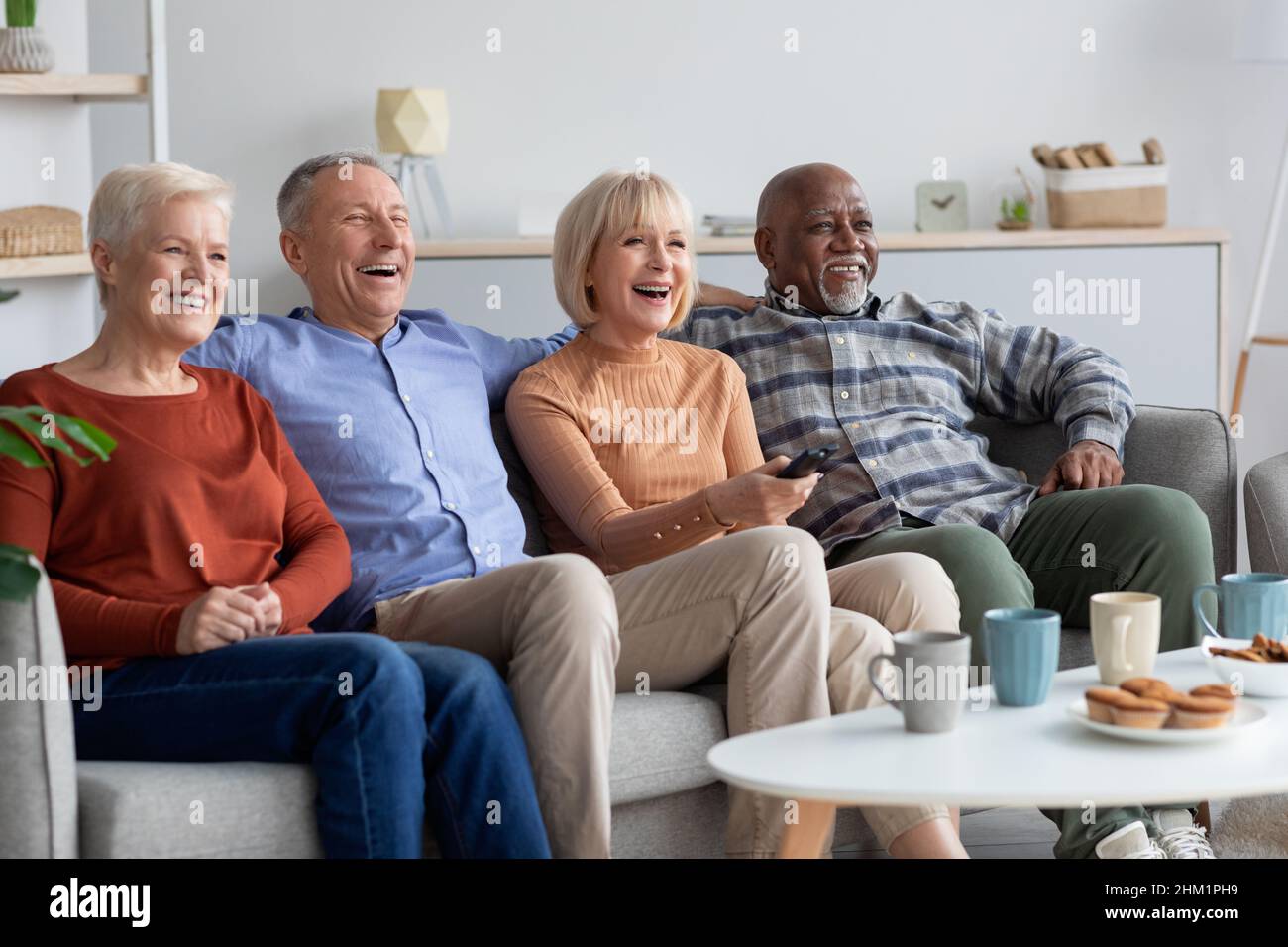 Multiracial friends senior people watching TV in the living room Stock Photo
