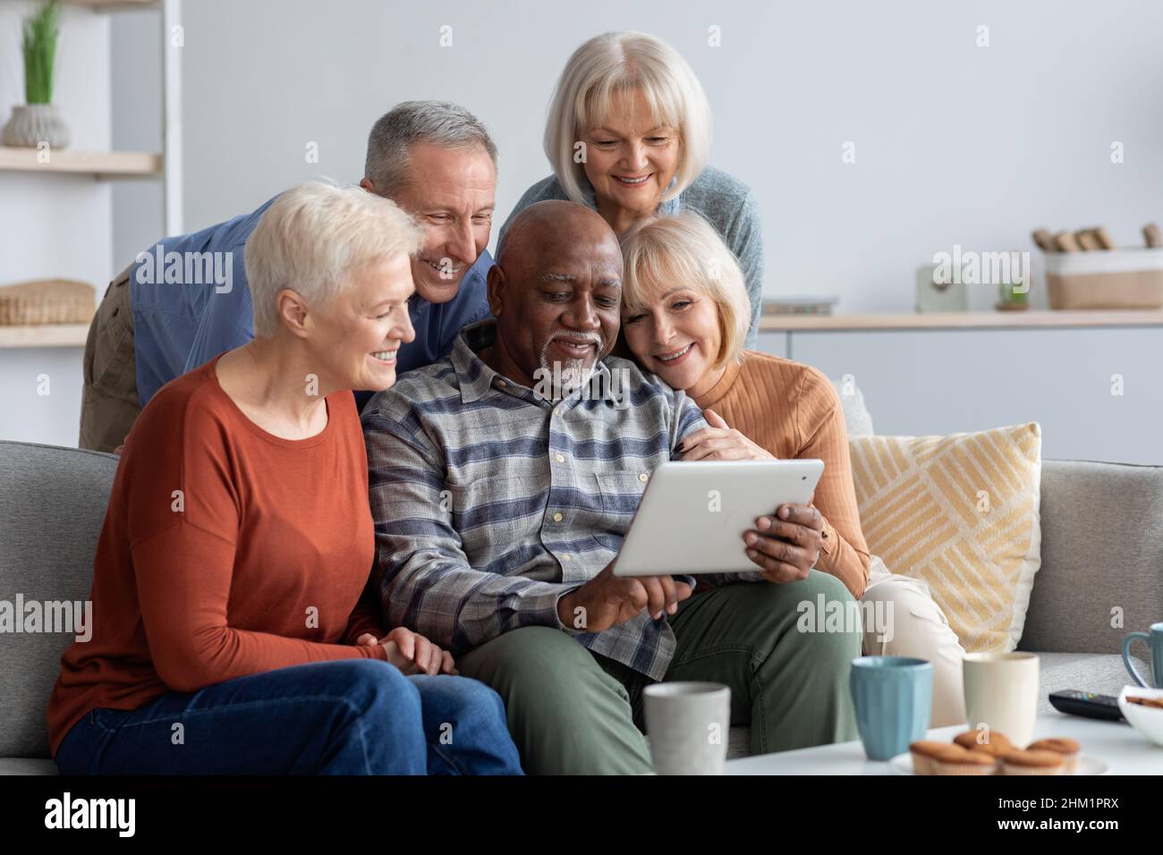 Happy elderly people spending time together at home, using gadgets Stock Photo
