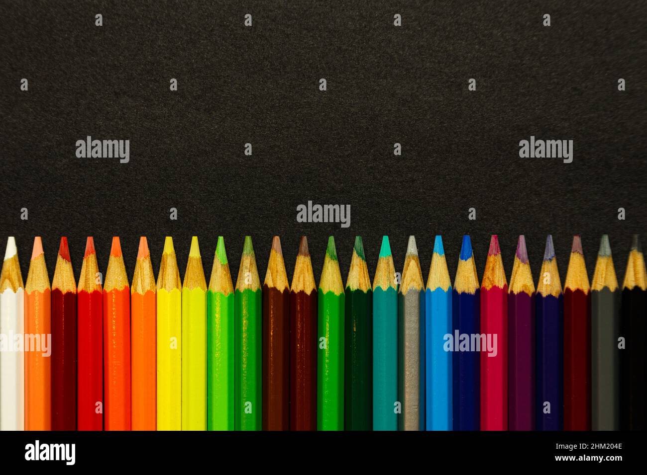Colorful pencils lined up over a dark background Stock Photo