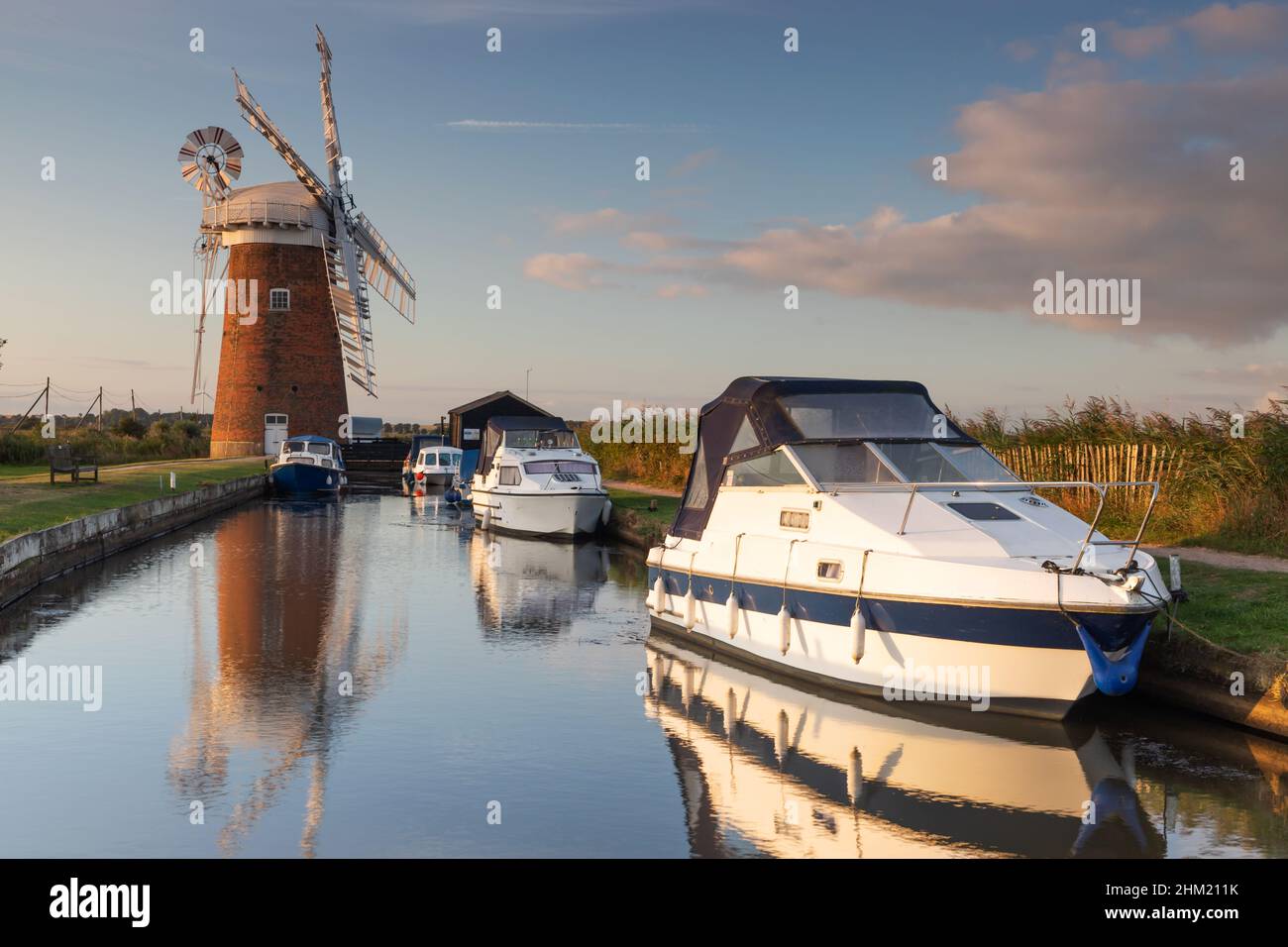Boats moored near Horsey Windpump on the Broads National Park in Norfolk, UK at sunrise Stock Photo
