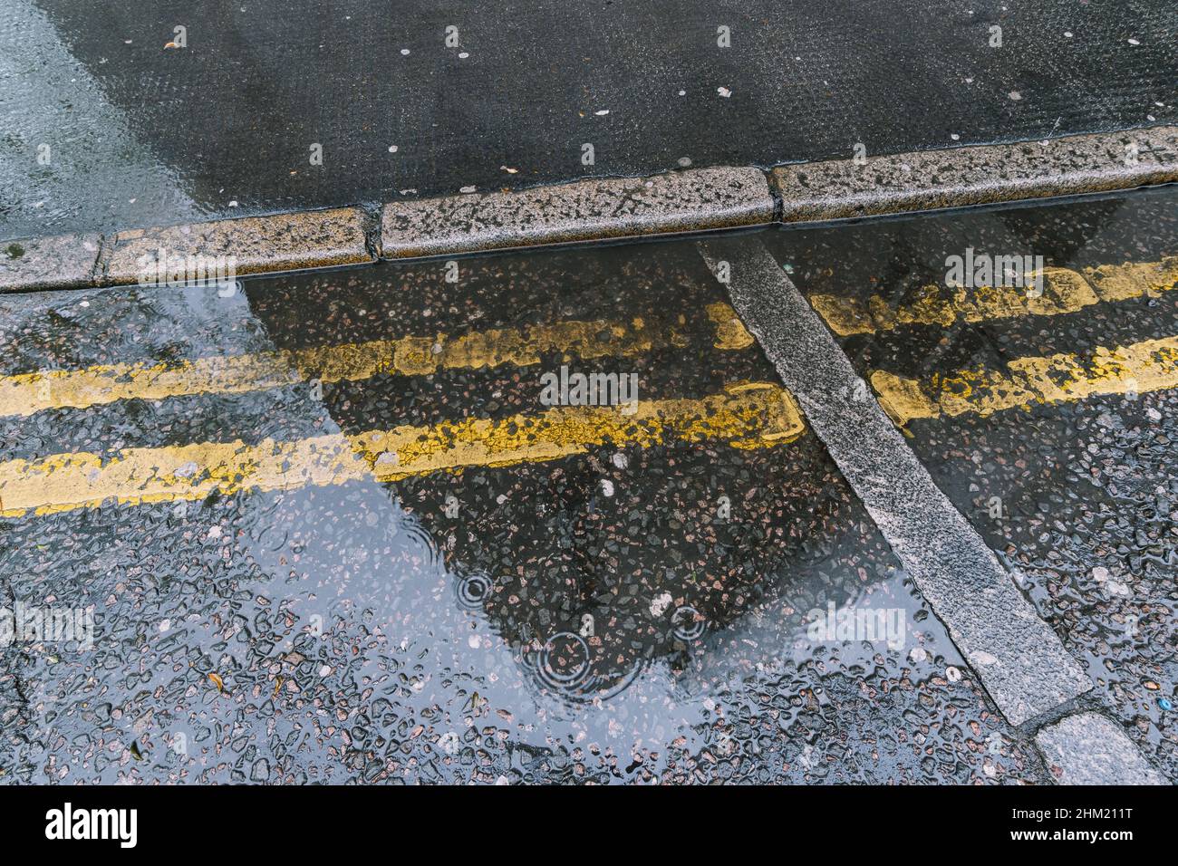 Rain drops rippling in a puddle with reflections in the street at london Stock Photo