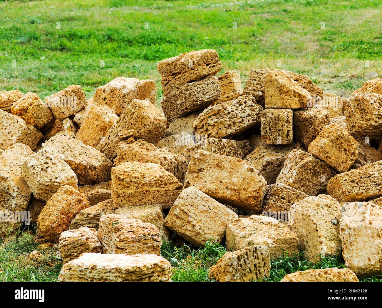 A pile of construction stone shell rock on a green lawn is scattered in ...