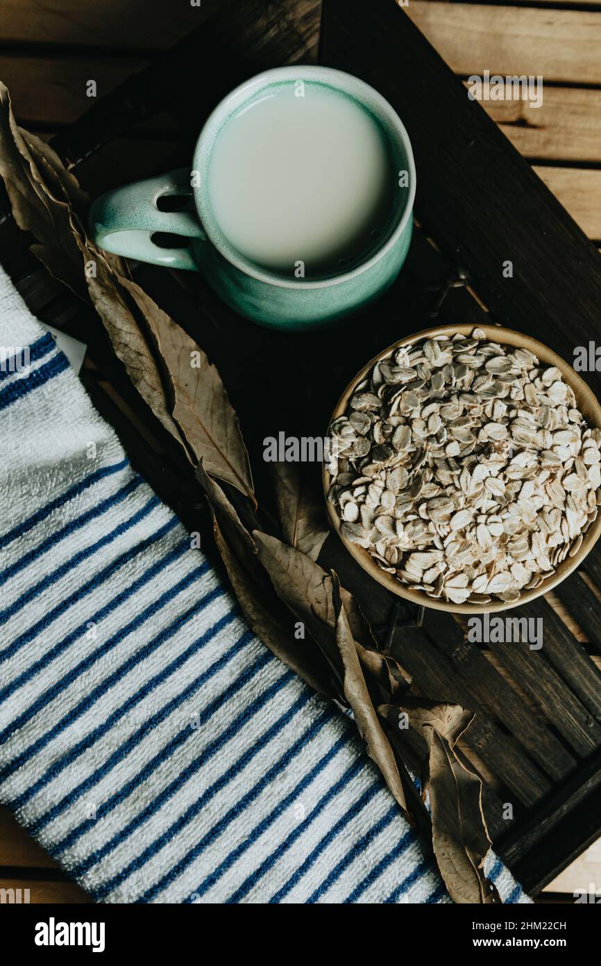 Cup of oat milk with oat seed on a bowl over a wooden plank Stock Photo