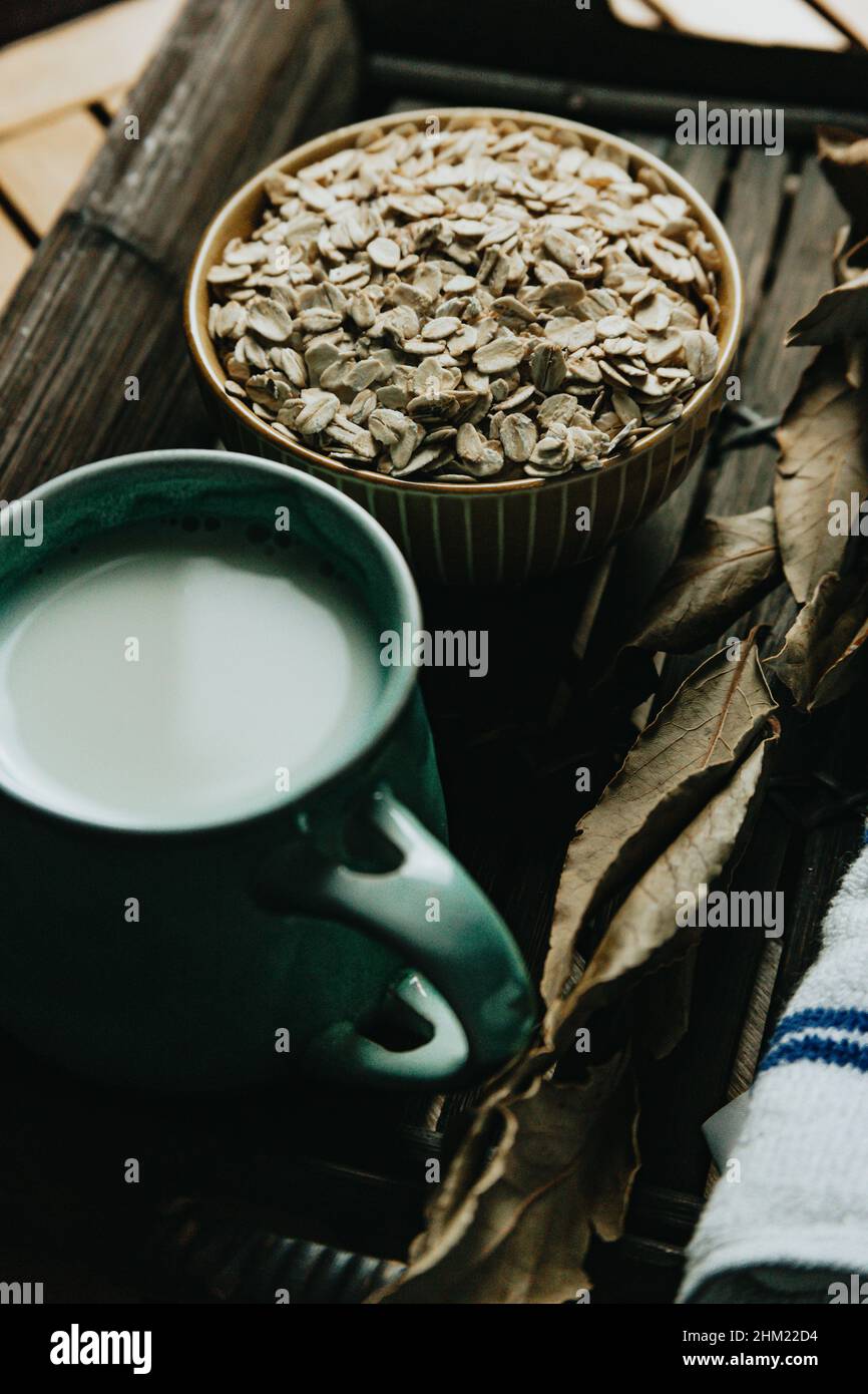 A breakfast of a cup of oat milk with oat seeds over a wooden plank Stock Photo