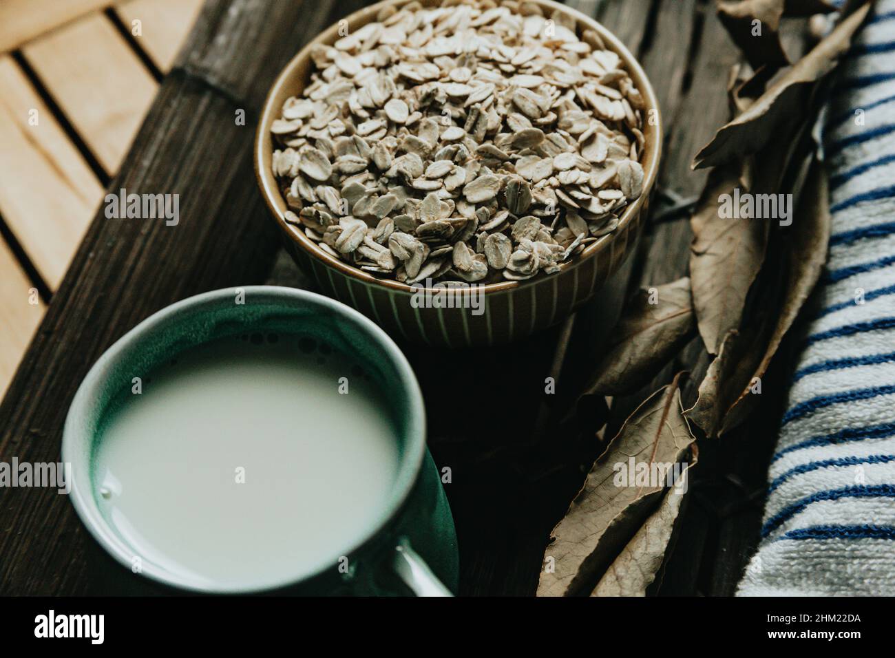 A breakfast of a cup of oat milk with oat seeds over a wooden plank Stock Photo