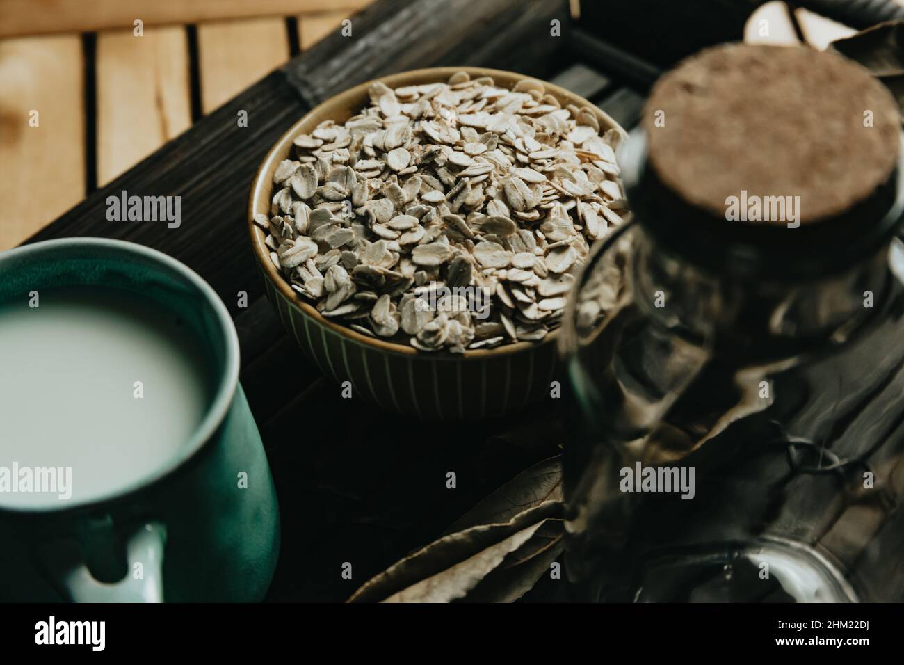 A breakfast of a cup of oat milk with oat seeds over a wooden plank Stock Photo