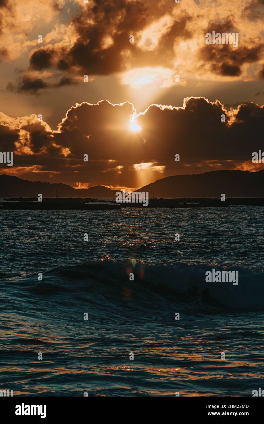 A massive sunset between the clouds with some islands over the ocean Stock Photo