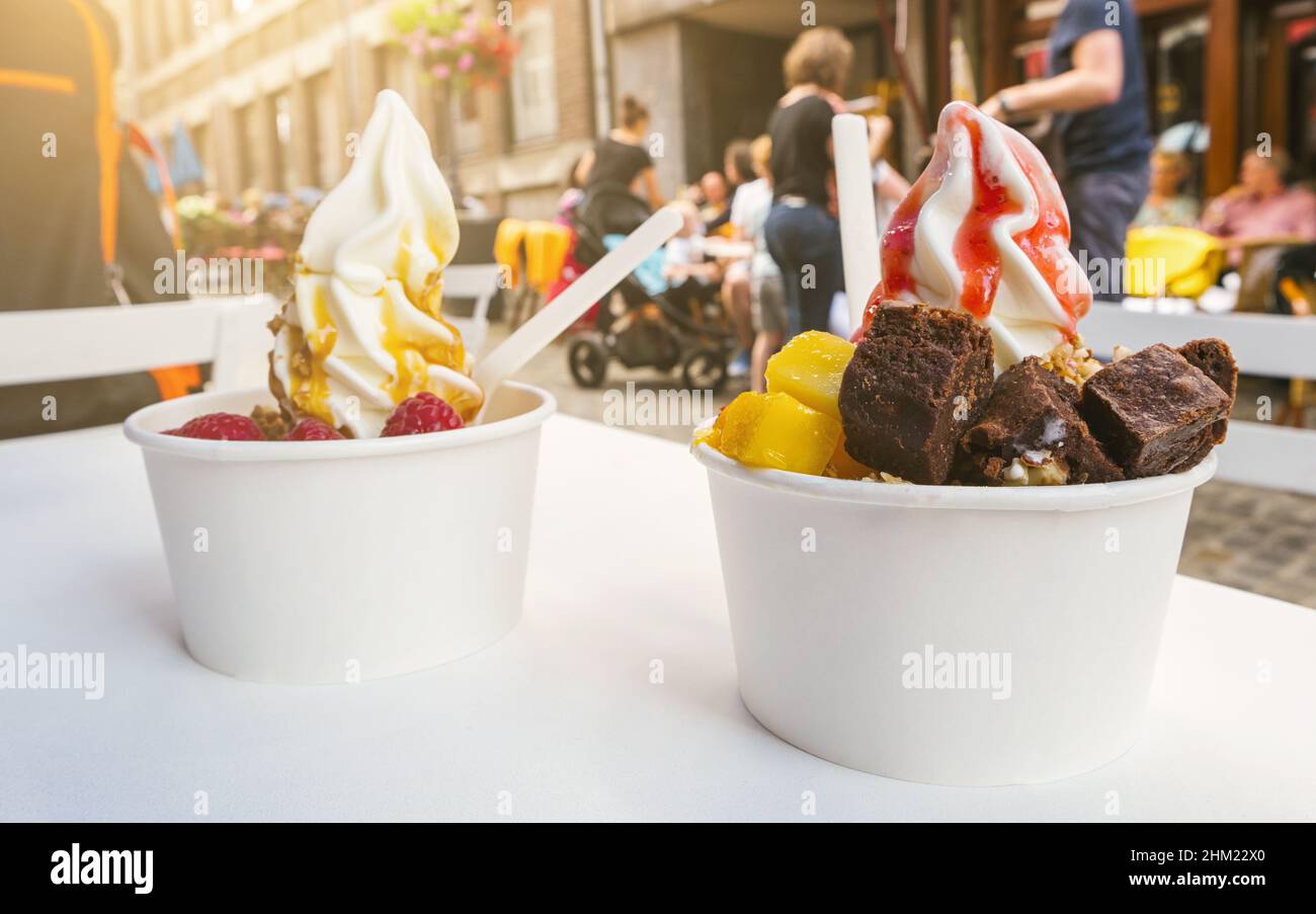 two frozen yoghurt cups with brownie and fruits toppings on a