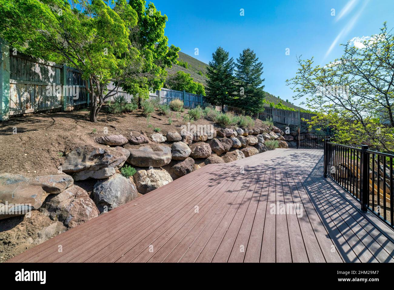 Hillside wooden deck with metal railings and a view of a slope of the