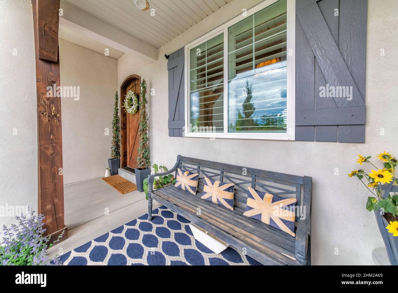 Decorated front porch with bench, flowers and carpet Stock Photo