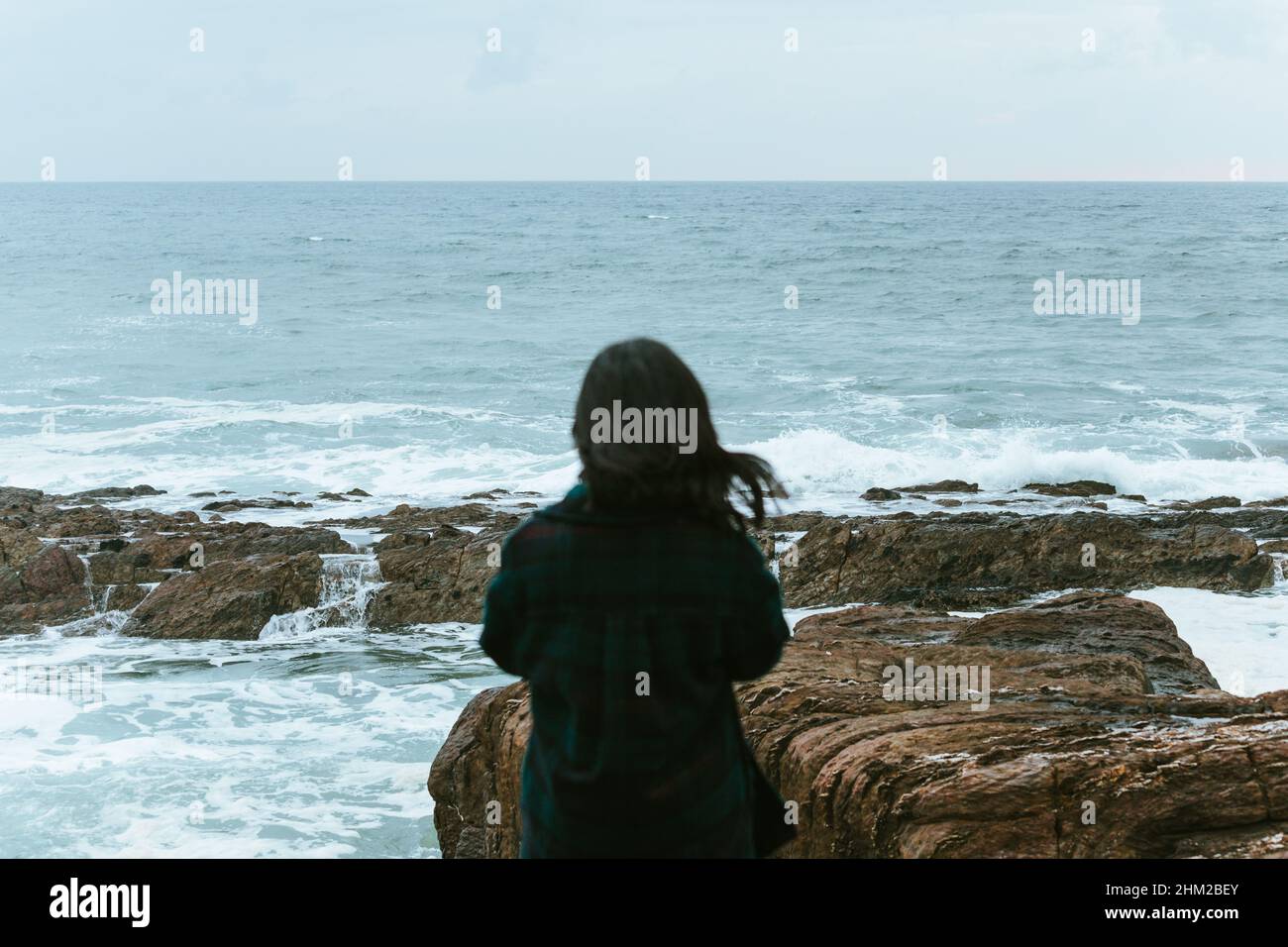Woman giving the back to the camera in front of a massive ocean with ...
