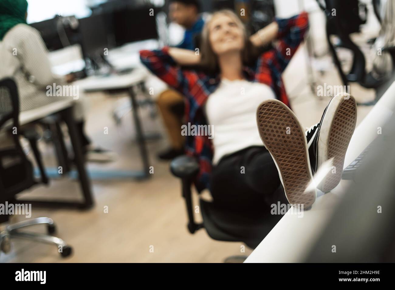 Casual business woman taking a break with legs on her table while ...