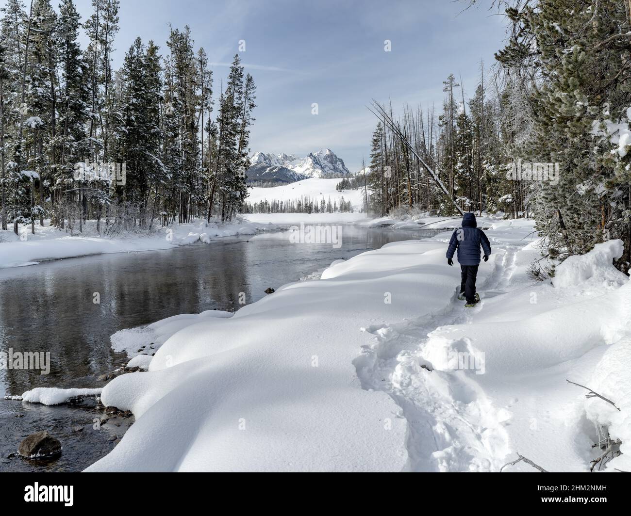 Snowshoes lead along a river to the distant mountains Stock Photo