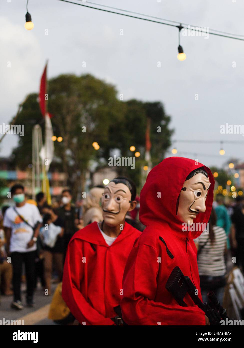 Palembang, South Sumatra, Indonesia. 7th Feb, 2022. The people of Palembang city wear Red Jumpsuits and wear the Salvador Dali masks from the Money Heist Serial character to entertain visitors at one of the tourist attractions in the city of Palembang, South Sumatra. Behind the costumes and colors have meaning, the red jumpsuit was also chosen because red is a symbol for revolution and has been used by many resistance groups throughout history. Meanwhile, the meaning of the masks is in addition to maintaining their original identity. Credit: ZUMA Press, Inc./Alamy Live News Stock Photo