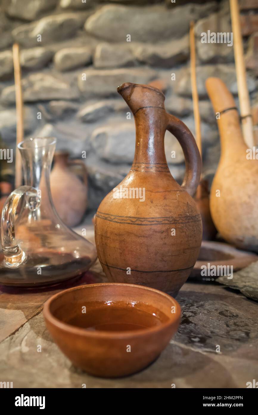 Young wine in clay bowl next to vintage terracotta jug in