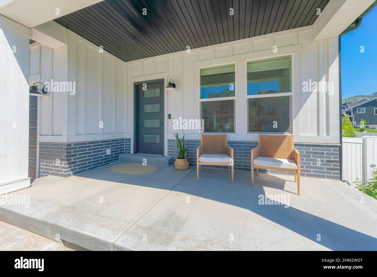 Exterior of a house with white board and batten and gray bricks sidings