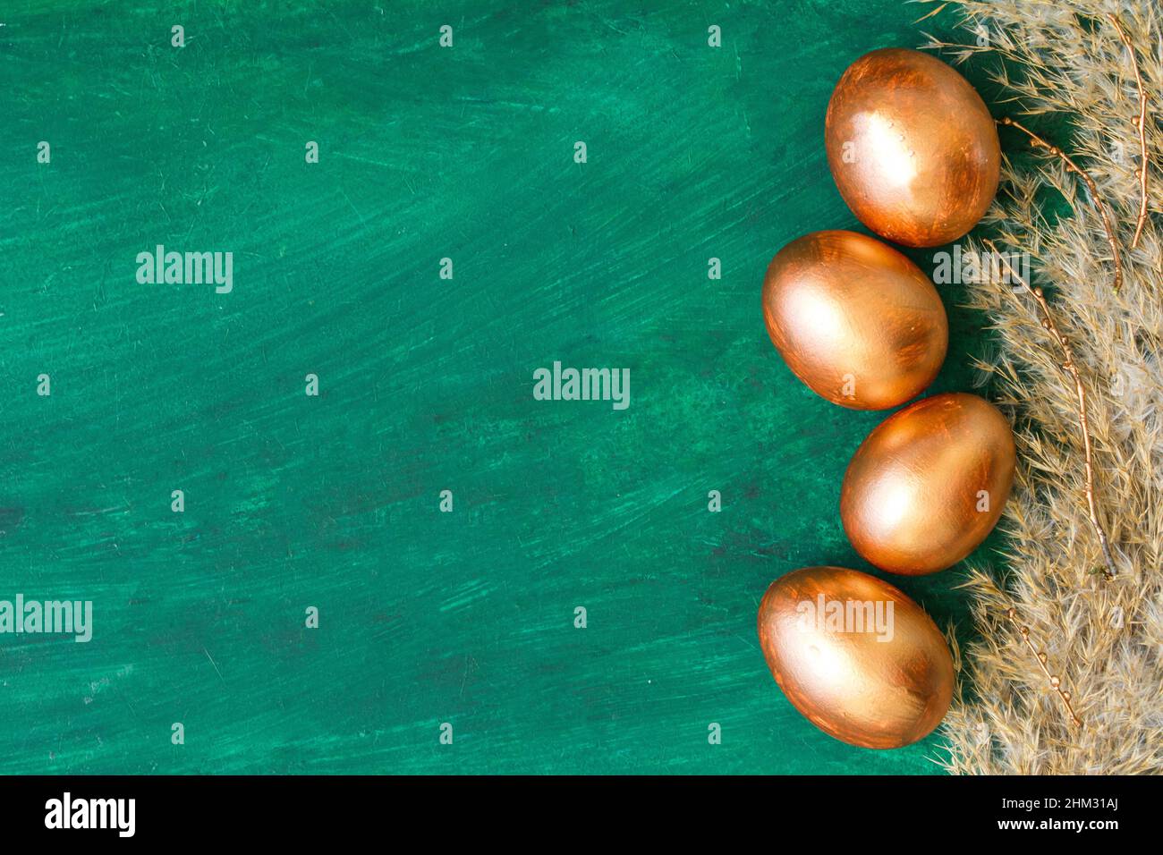 Golden Easter eggs and golden branches, reeds on a green watercolor background. Banner. Layflat. Space for text Stock Photo