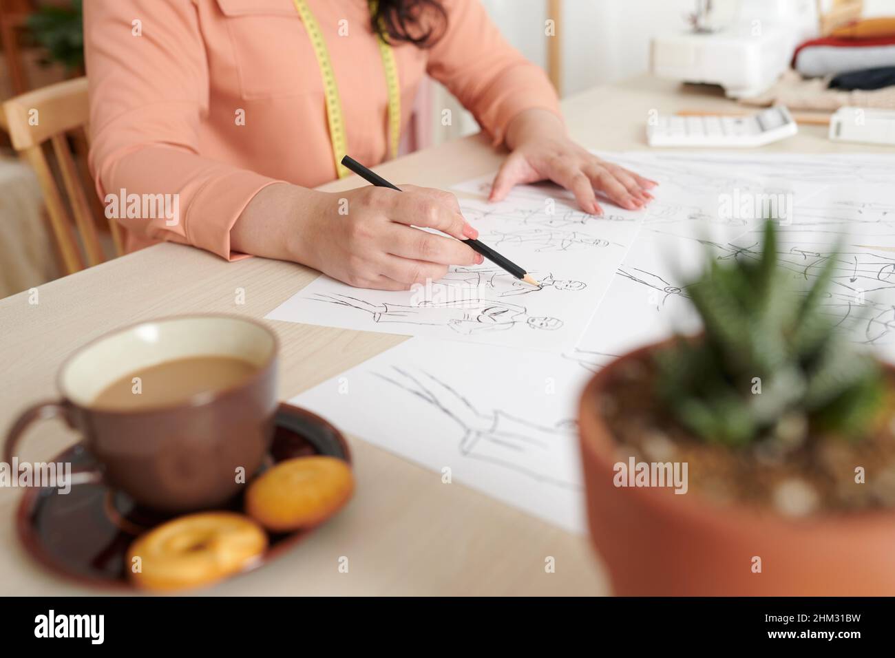 Dressmaker work on sketches for new collection at her desk in studio ...