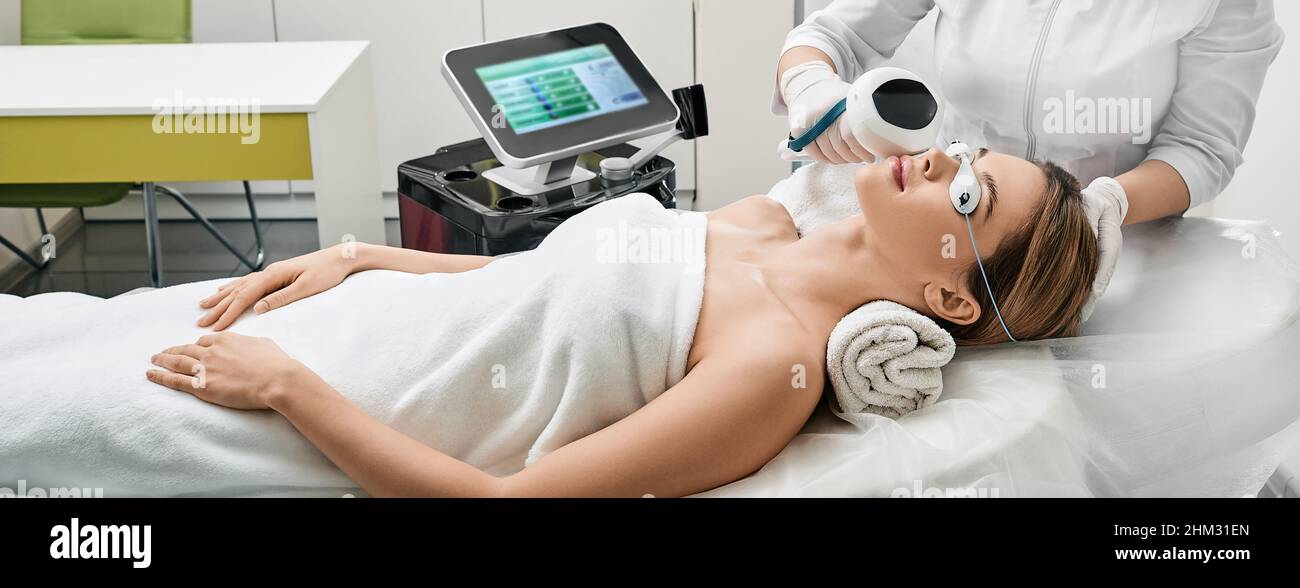 Face rejuvenation with intense pulsed light apparatus. Woman during IPL procedure for her face at beauty clinic to remove brown spots and treat rosace Stock Photo